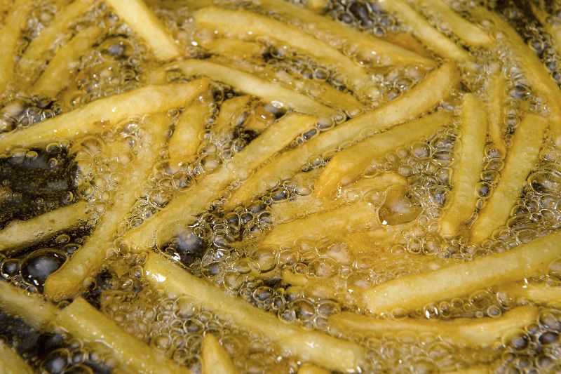 Freir patatas con aceite en freidora